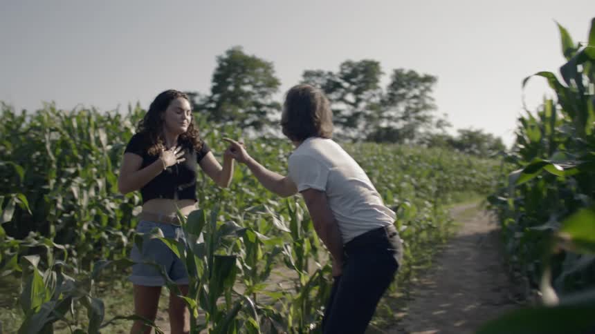 Couple laugh and play in corn field