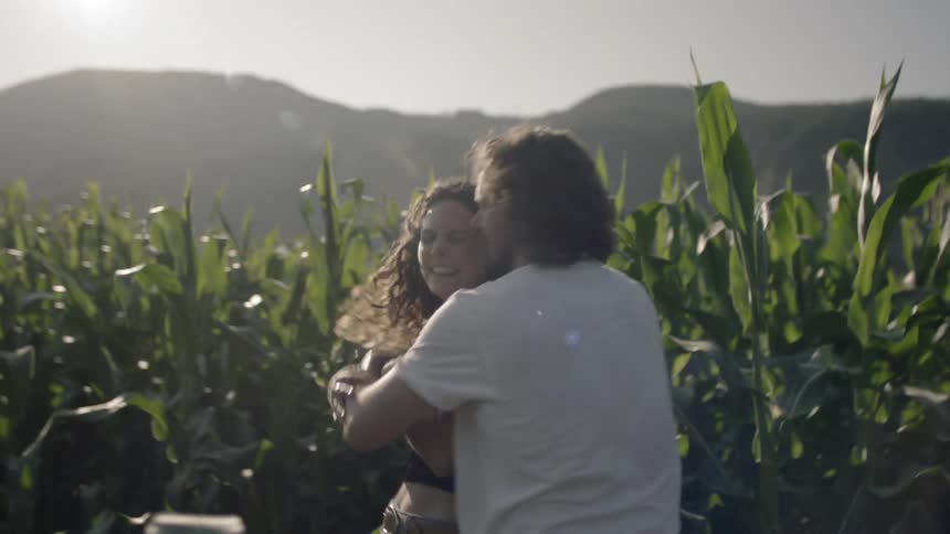 Young couple playing and hugging in a cornfield while out on a date