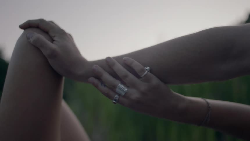 A person with rings on their fingers glides their hand down another person's arm