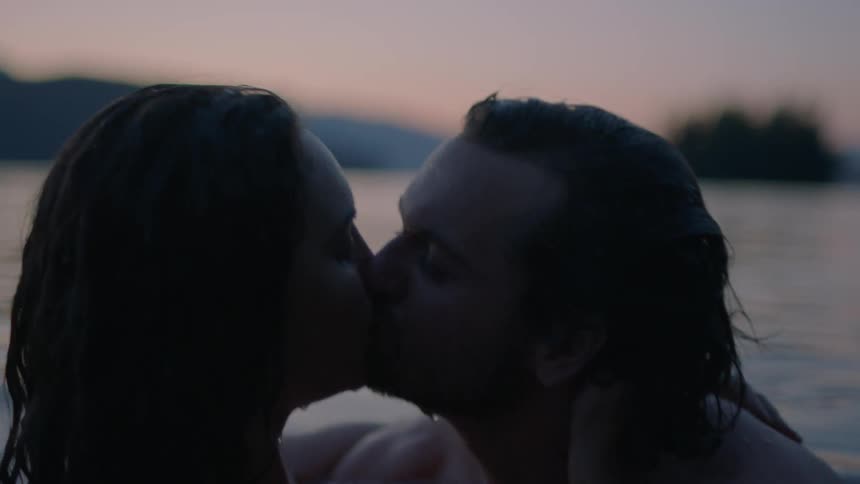 Man and woman kiss in the lake at dusk