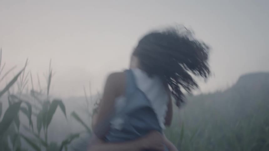 Man and woman hug each other in a green field