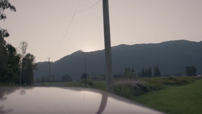 Vehicle drive along road past fields toward mountain