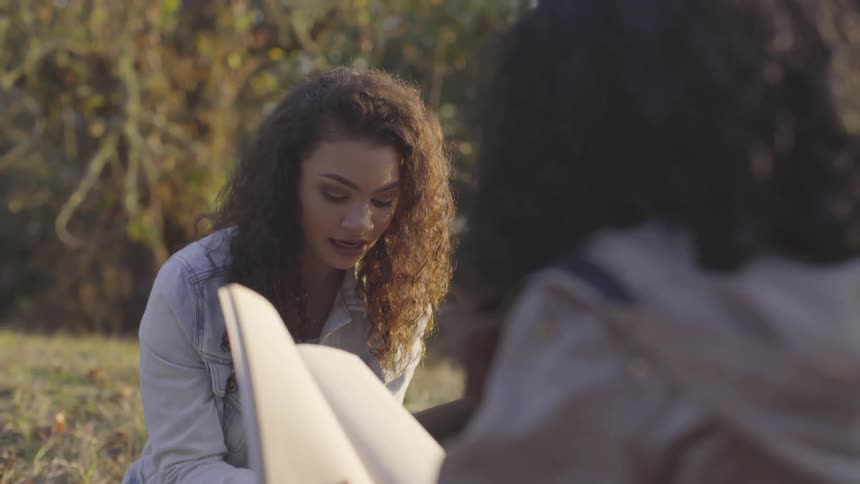 Two women sit outside reading