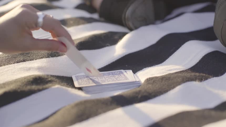 A person draws cards from a striped blanket