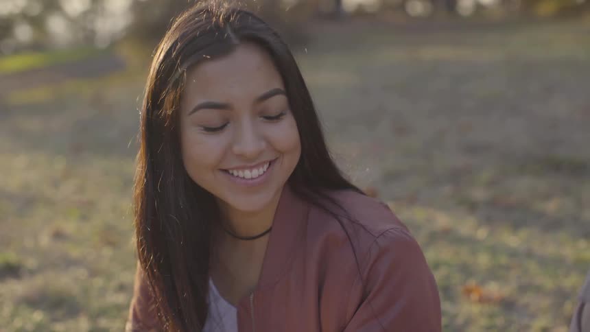 A woman laughs while sitting on the ground