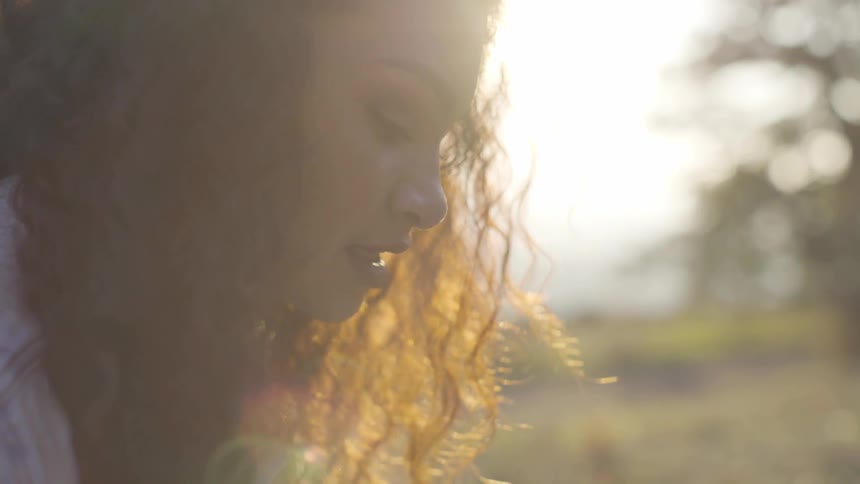 A woman looks down while outdoors speaking