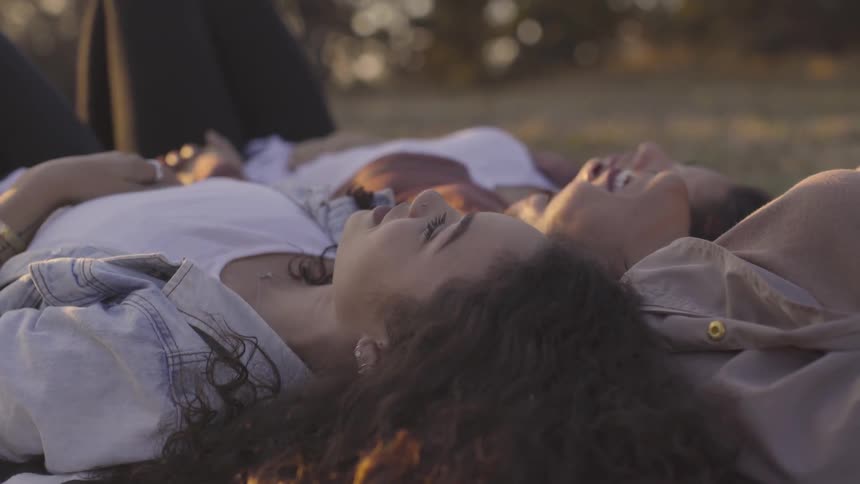 Three women lay on the grass looking up