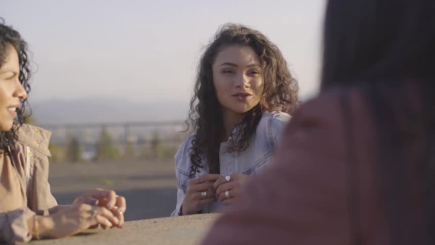Three woman sitting on a table outside talking