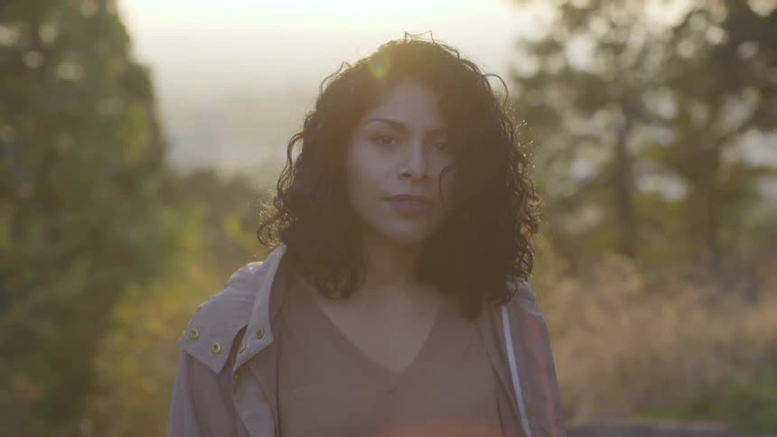 A woman raising her head to look at the camera while standing outdoors