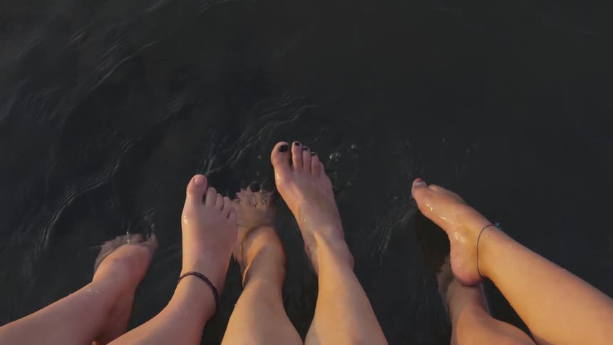Three people put their feet in water outside