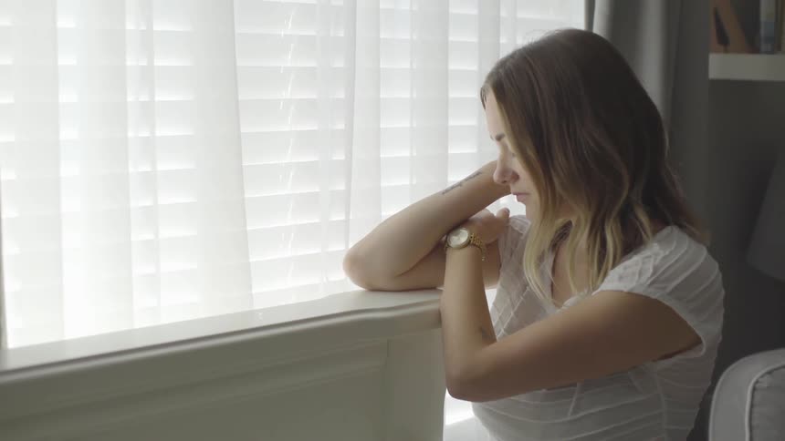 A woman inside sitting next to a window