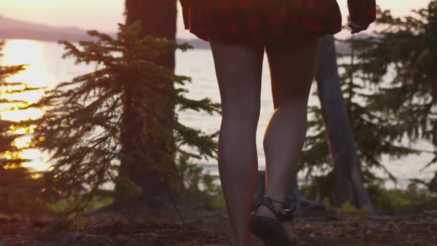 A woman walks in the woods toward the coast line