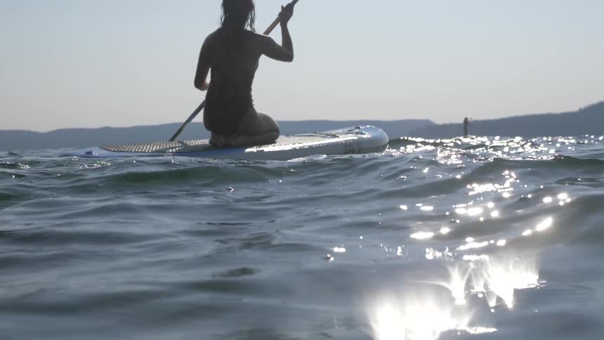 A woman paddles on a stand up paddle board