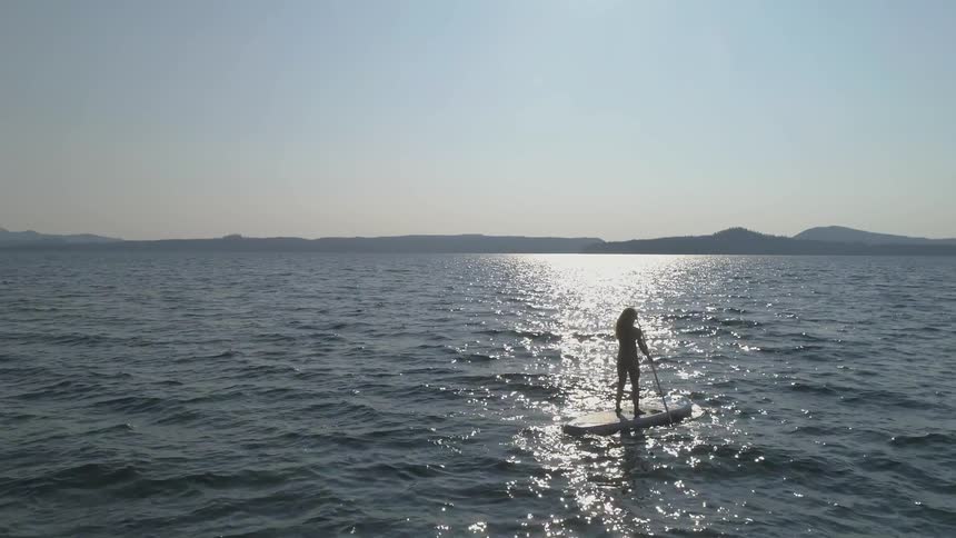 A person paddles across a lake on a paddle board