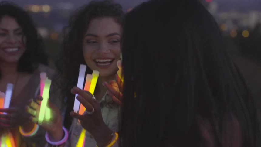 Women laugh as they play with glow sticks