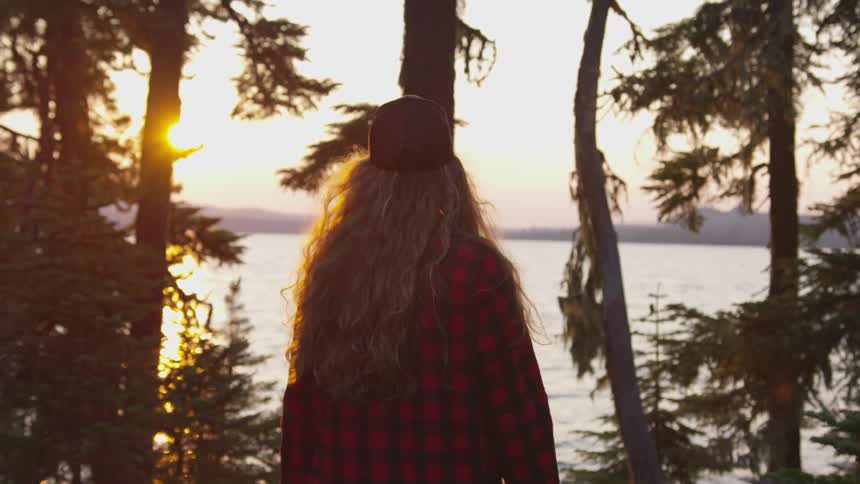 A woman walks through a forest looking around
