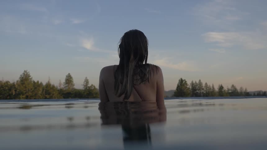 A woman stands in water looking out over a lake