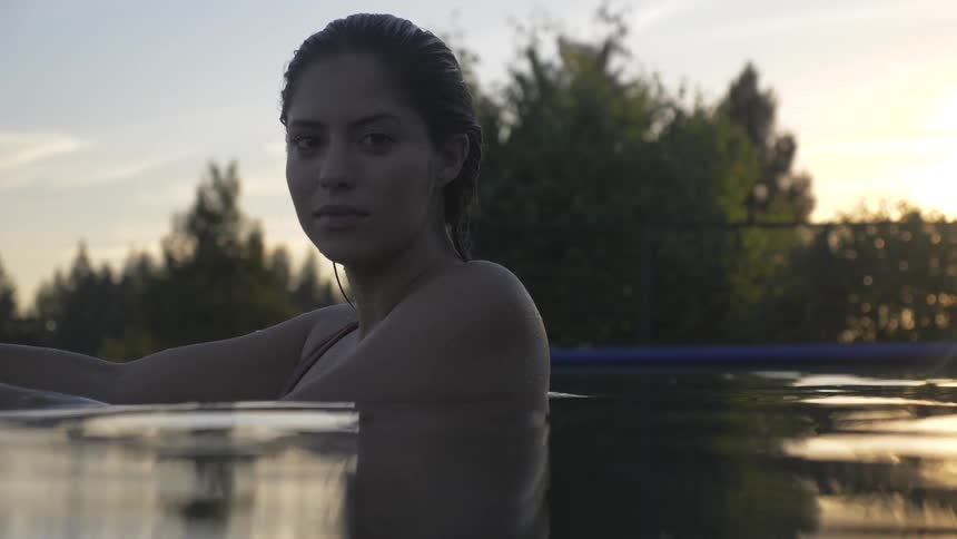 A white woman turns her head while partially submerged in a pool