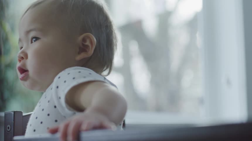 A baby standing in a chair at a table