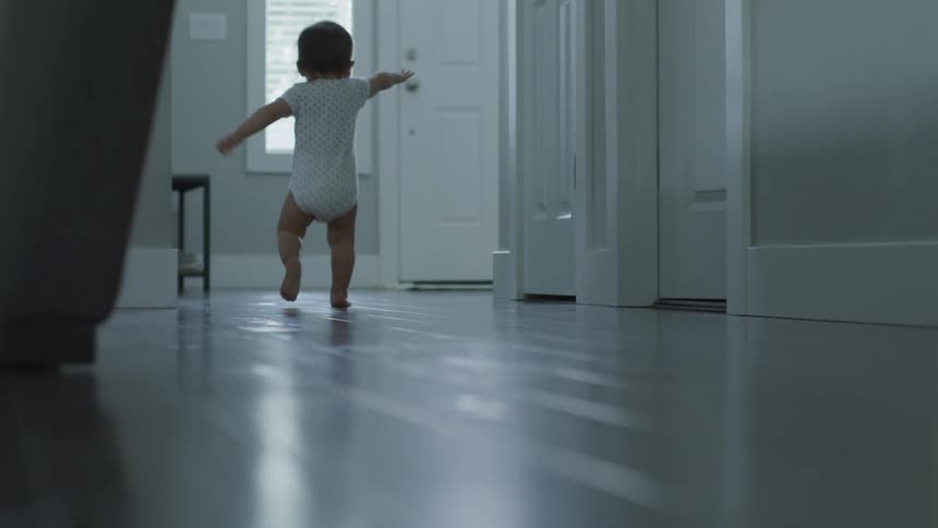 A baby walks down a hallway