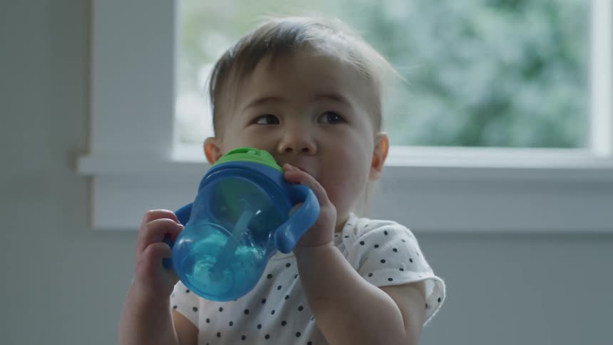A toddler drinks from a sippy cup