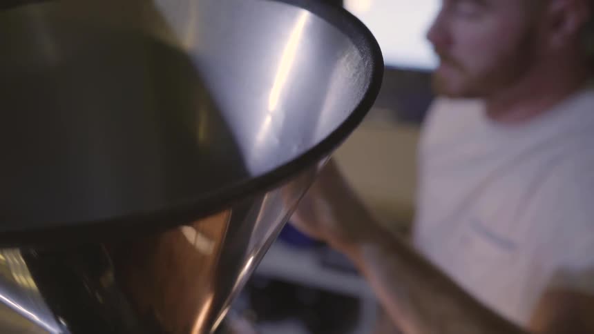 A man uses an industrial coffee grinder