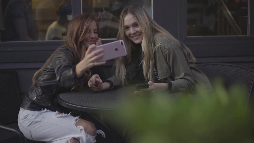 Two women take selfies at a table