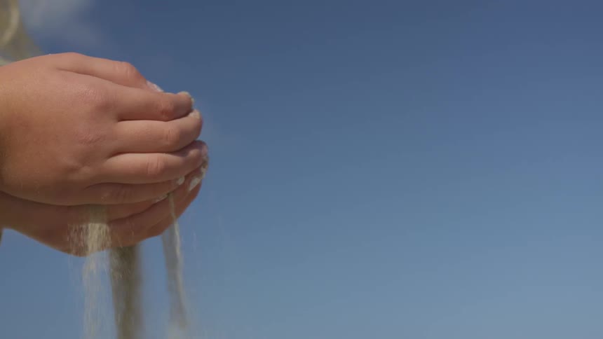 Sand drips through clasped hands