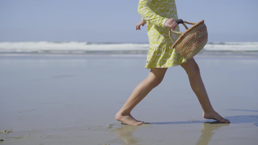 A young white girl walks across a beach
