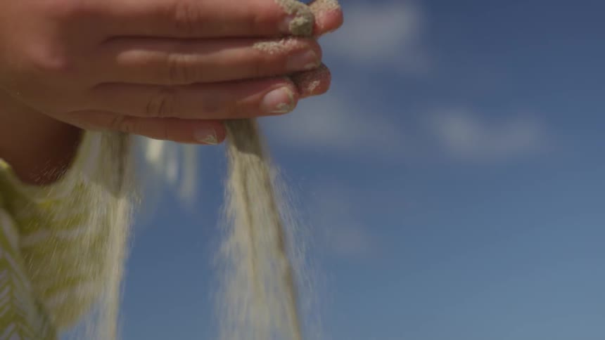 Sand is falling from a persons hands