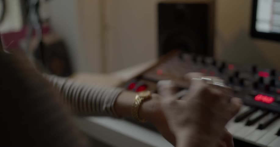 A woman plays a keyboard and then looks at her wristwatch