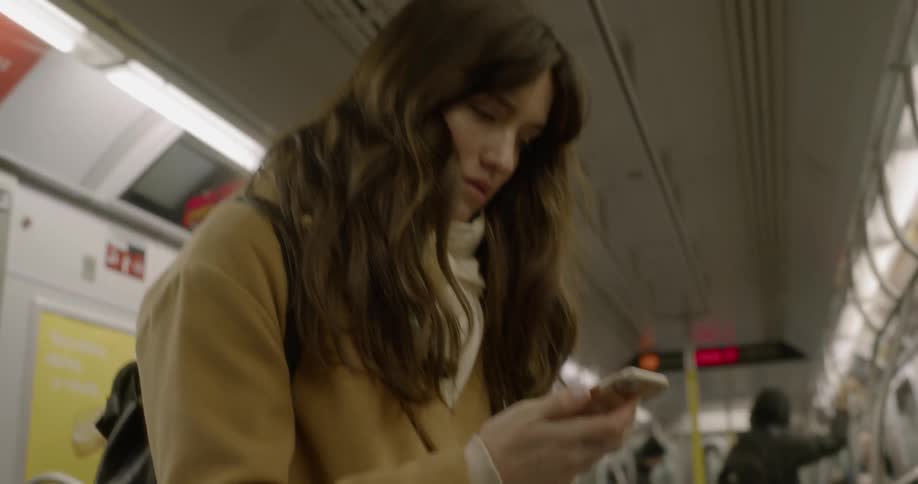 A woman checks her smartphone on the subway