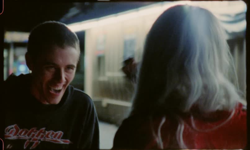 A man and a woman talking at night near a gas station