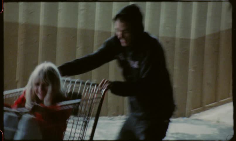 A man pushes a woman around in a shopping cart
