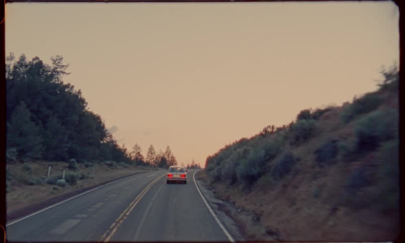 A car drives down a highway through a remote area