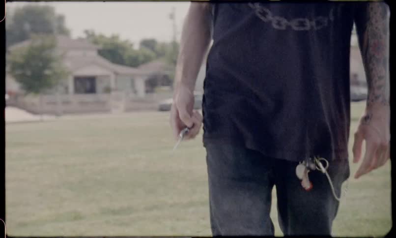 A man opens a knife and walks across a field