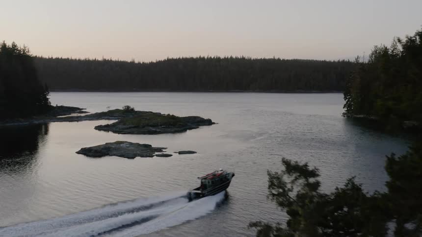 A boat powers across a lake in the forest