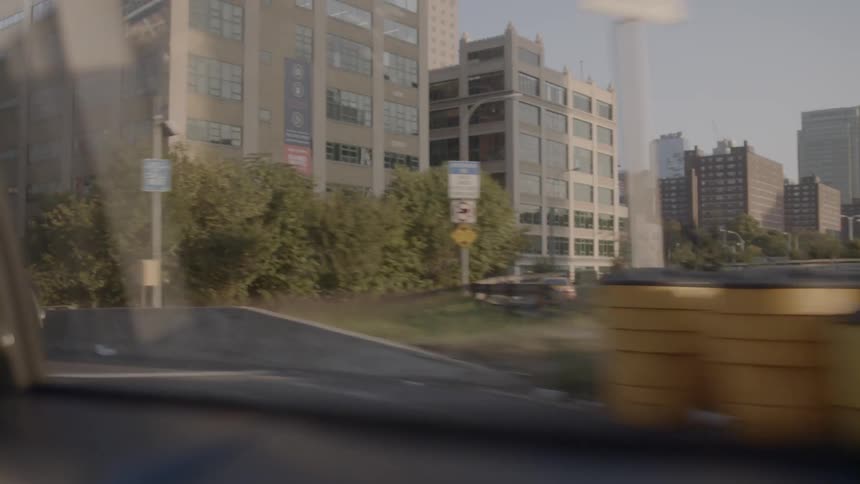 A car passes another car on the highway in the way towards a dense city