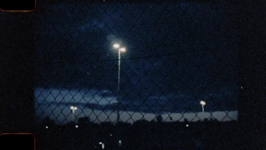 Vintage footage of a night sky over a parking lot