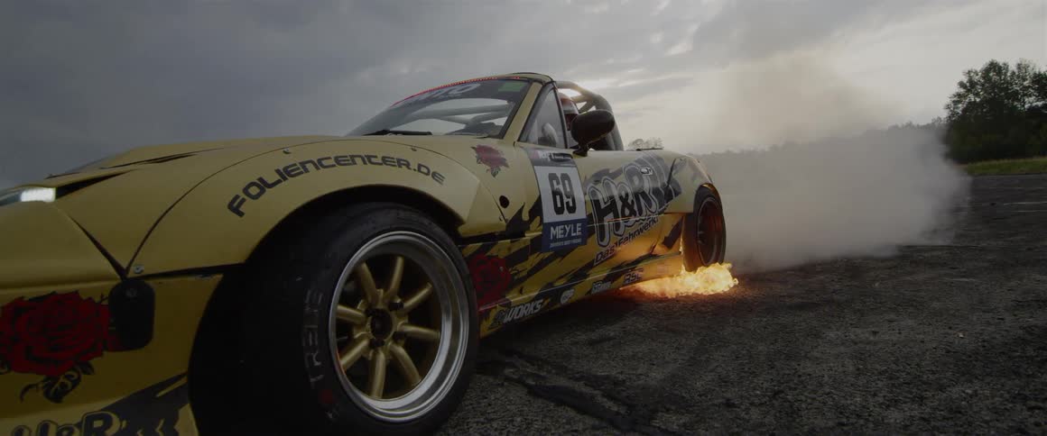 A race car does a burnout with flames coming out the back