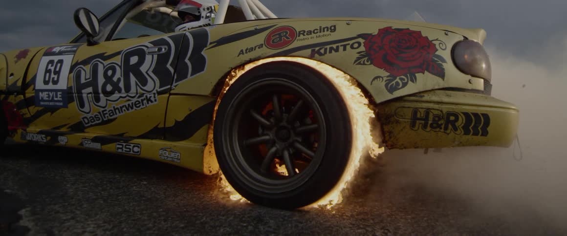 A car revving with its back tire on fire