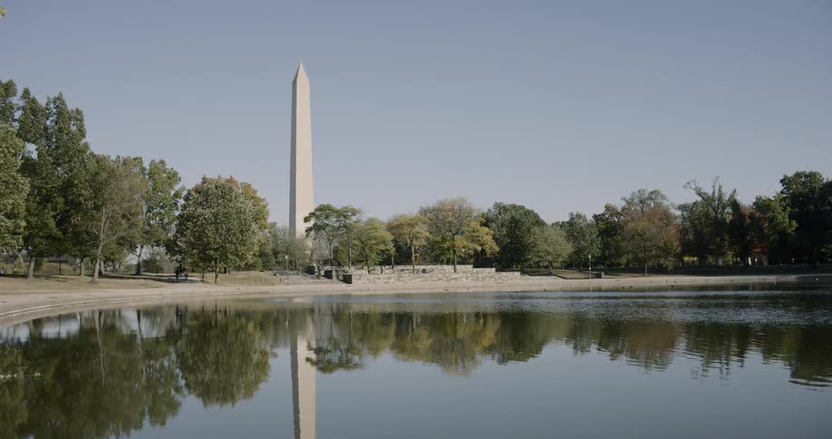 A pond with trees and a monument in the background