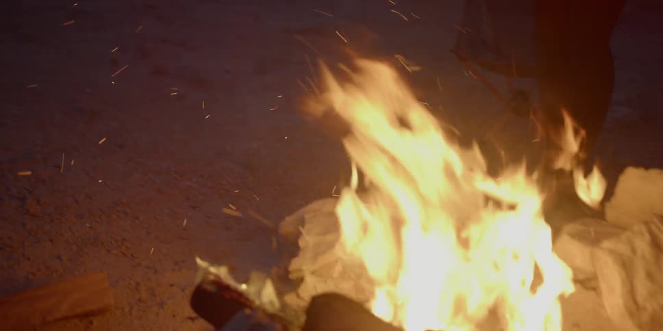 Woman throwing wood on a campfire