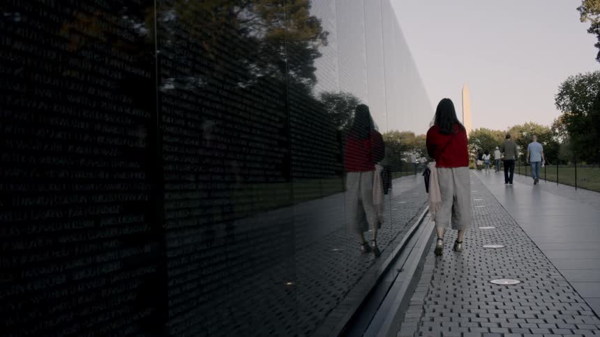 A woman walks next to the vietnam war memorial