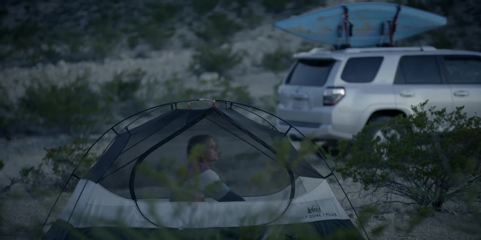 A woman stretches and sits up in a tent