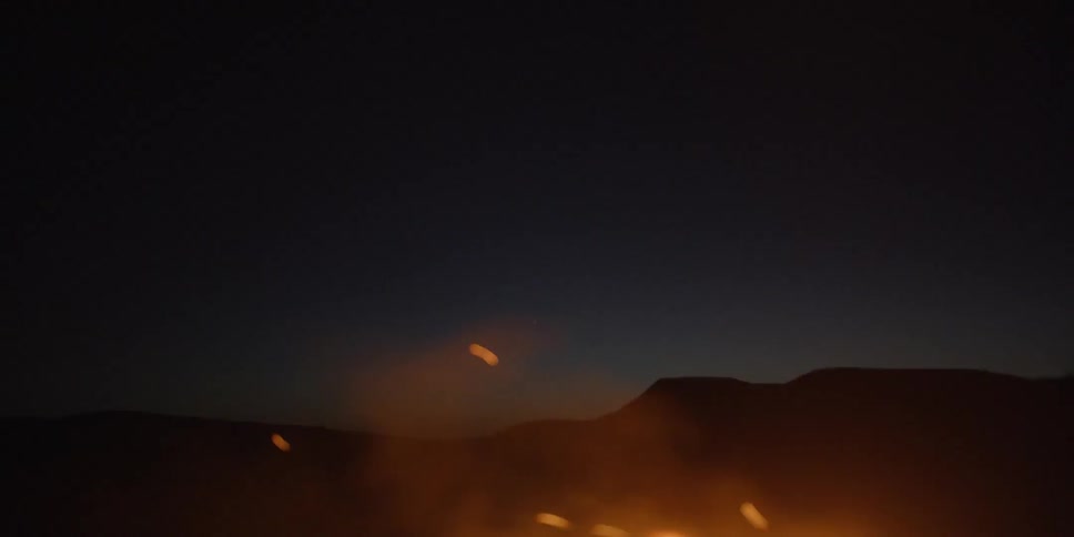 A bonfire burning at night with the sky in the background