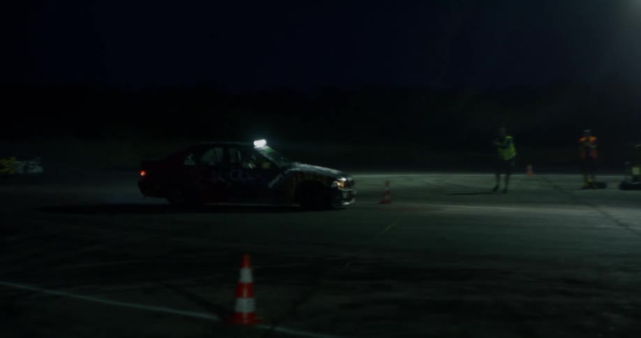 A car drifts around a corner on a track at night