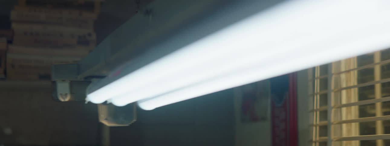 A fluorescent light swings and flickers while hanging from a ceiling