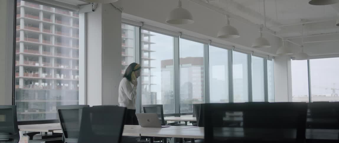 A white woman talks on the phone while walking in an office