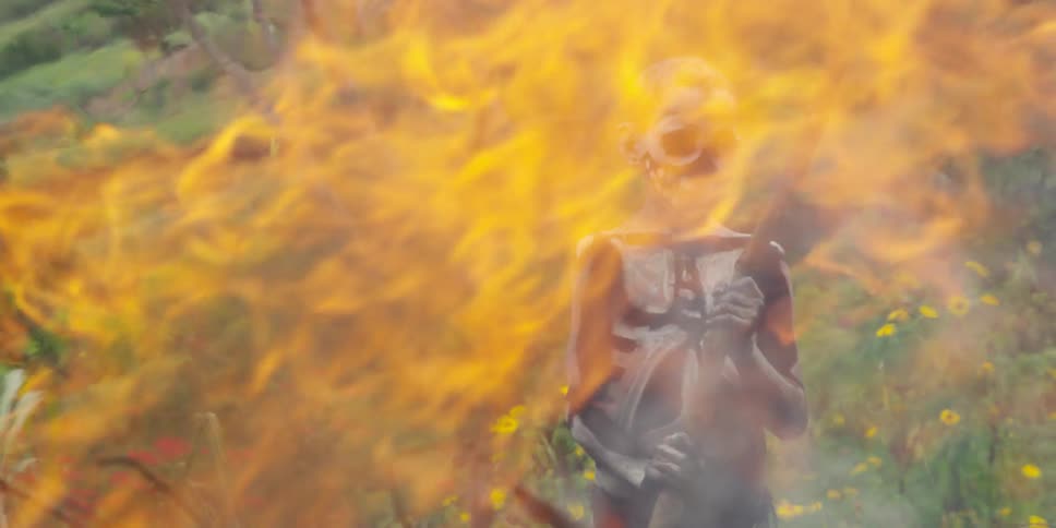 A fire burns in front of a native boy in skeleton paint